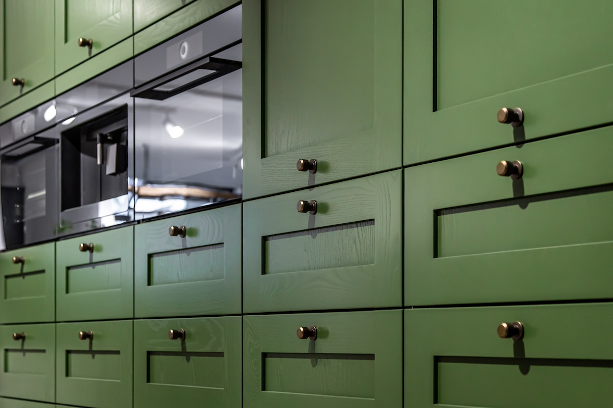 Large green kitchen cabinet with many handles close-up